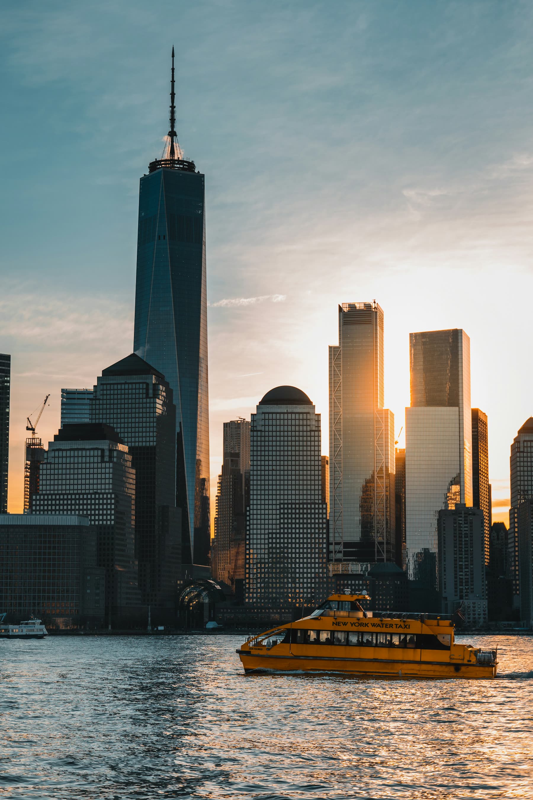 Lower Manhattan skyline at golden hour with a New York water taxi crossing the Hudson